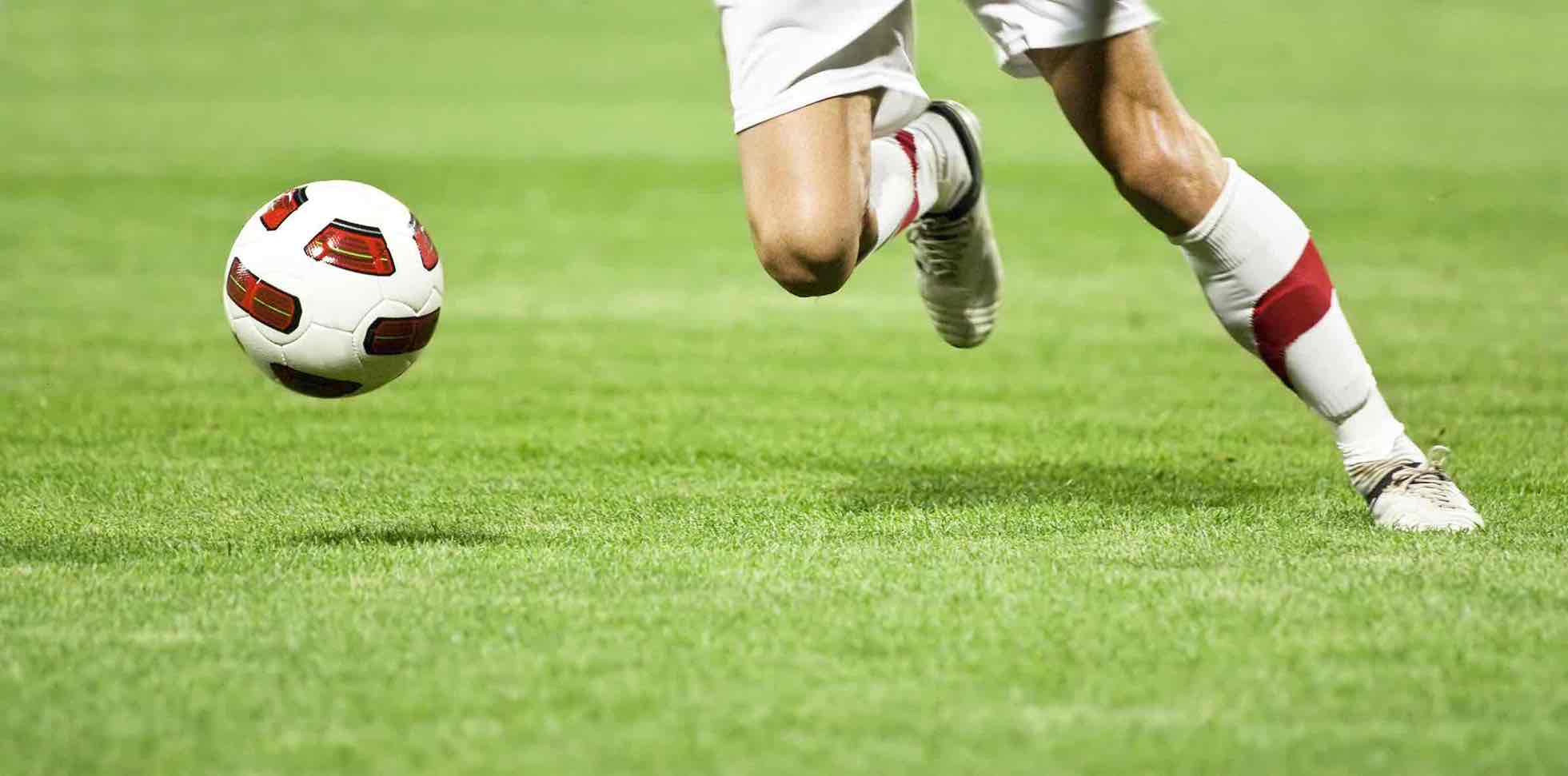 Close-up of a footballer pivoting on the pitch with focus on the right knee (ACL)