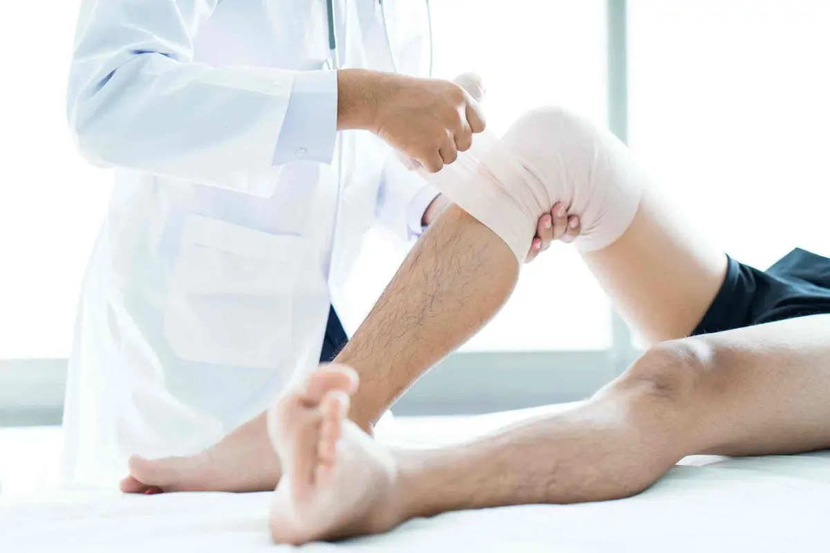 Doctor applying a bandage to a patient's knee after surgery