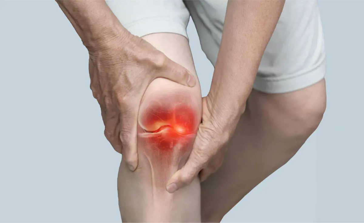 Knee arthritis clinic in Reading — Mr Sam Nahas Man holding his knee in pain while standing, close-up of the knee (knee arthritis)