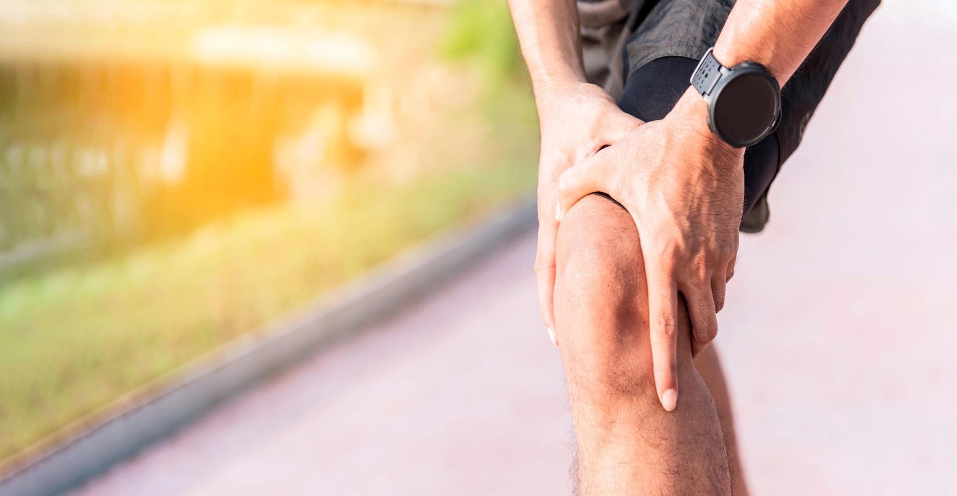Runner holding the knee with acute pain and instability
